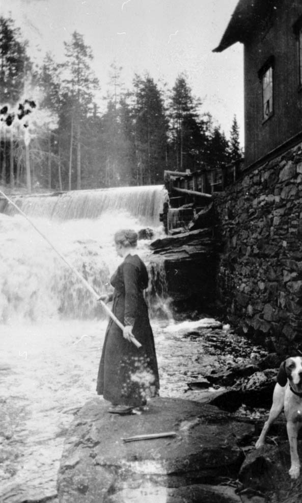 Olga Sagbakken fisker i Sagbakk-fossen, hunden Ravn. 1920-1922.
