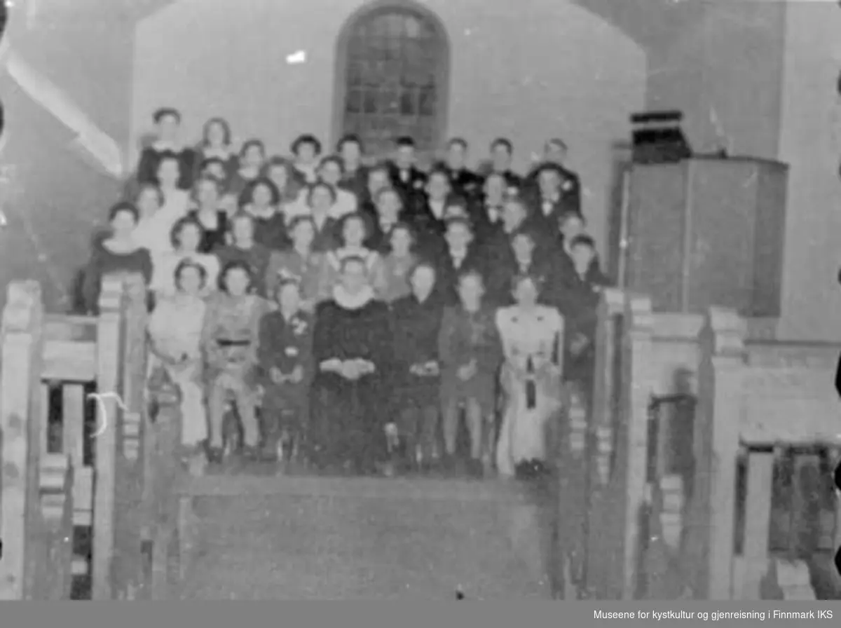 Konfirmanter fotofgrafet inne i kirken - fra Åshild Bomnes konfirmasjon. Pastor Gunnar Dahl i midten på første rekke. Sannsynligvis er bildet fra før renoveringen av kirken 1939/1940.