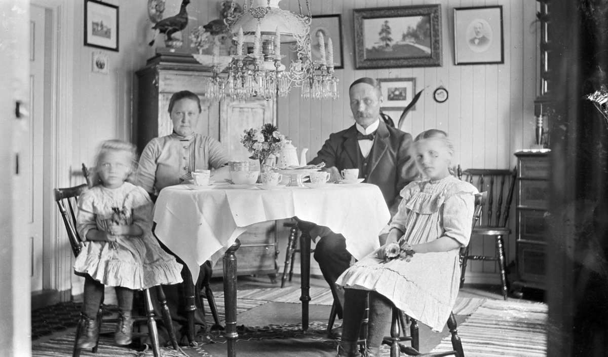 Interiør stue. Voksne og barn ved kaffebordet. Daniel Lysrud (1874-1951) med hustru Karen Taskerud (1883-1945) og døtrene Alida f.1904 og Astrid (1909-1988).