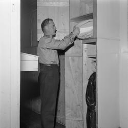 Lademoen brannstasjonen.  Brannmann ordner i skapet.