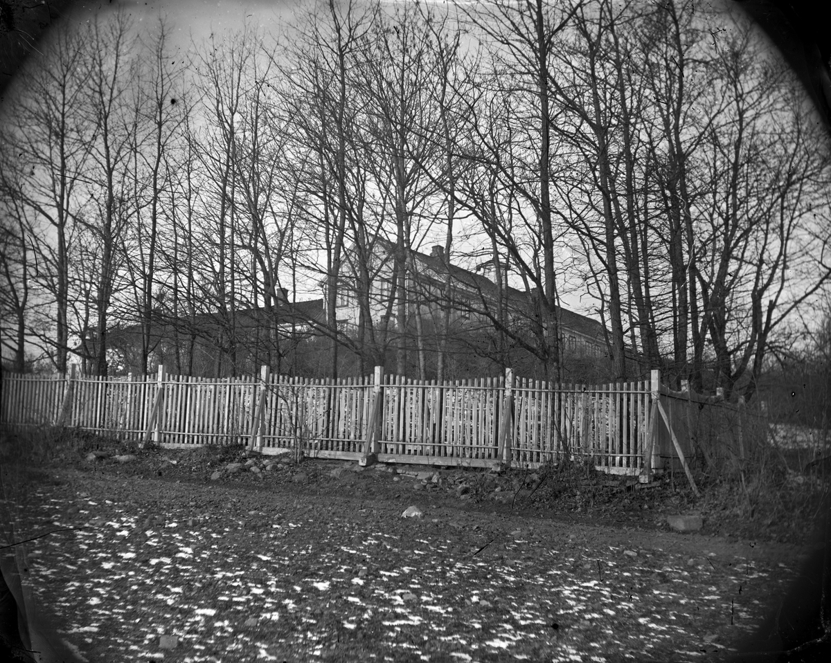Hovinsholm gård, Helgøya i Ringsaker. Hovedbygningen sett fra gravstedet. Gjerde, stakitt. Foto Jacob Hoel, 