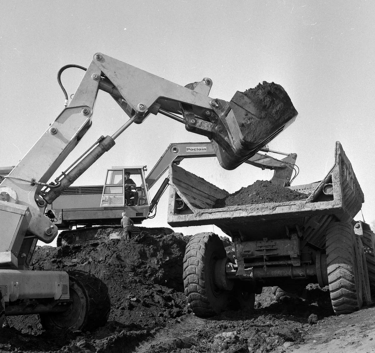 To gravemaskiner og en dumper. Den forreste gravemaskinen er en forgraver, trolig Munck, som ble produsert på Hamar.