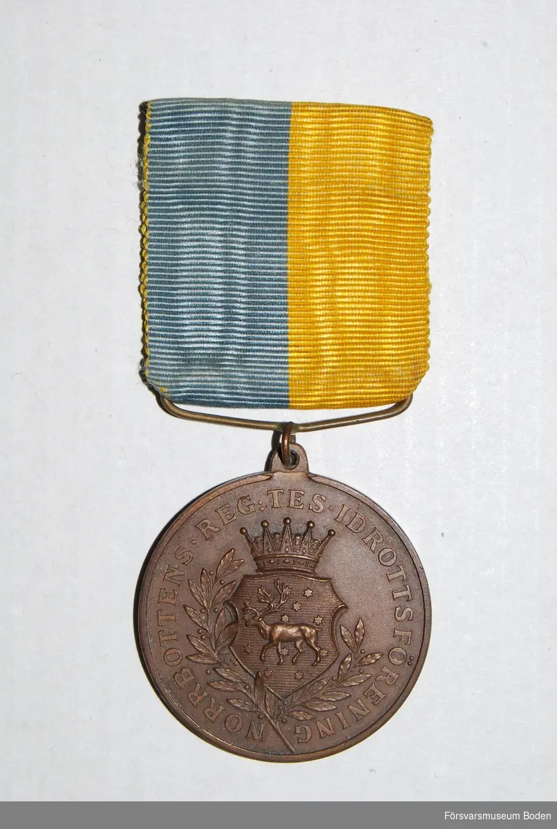 Med medaljband i blått och gult. Sköld med regementets vapen på åtsidan. Frånsidan har texten "För Sverige" med lagerkvist samt tom plats för namngravyr.