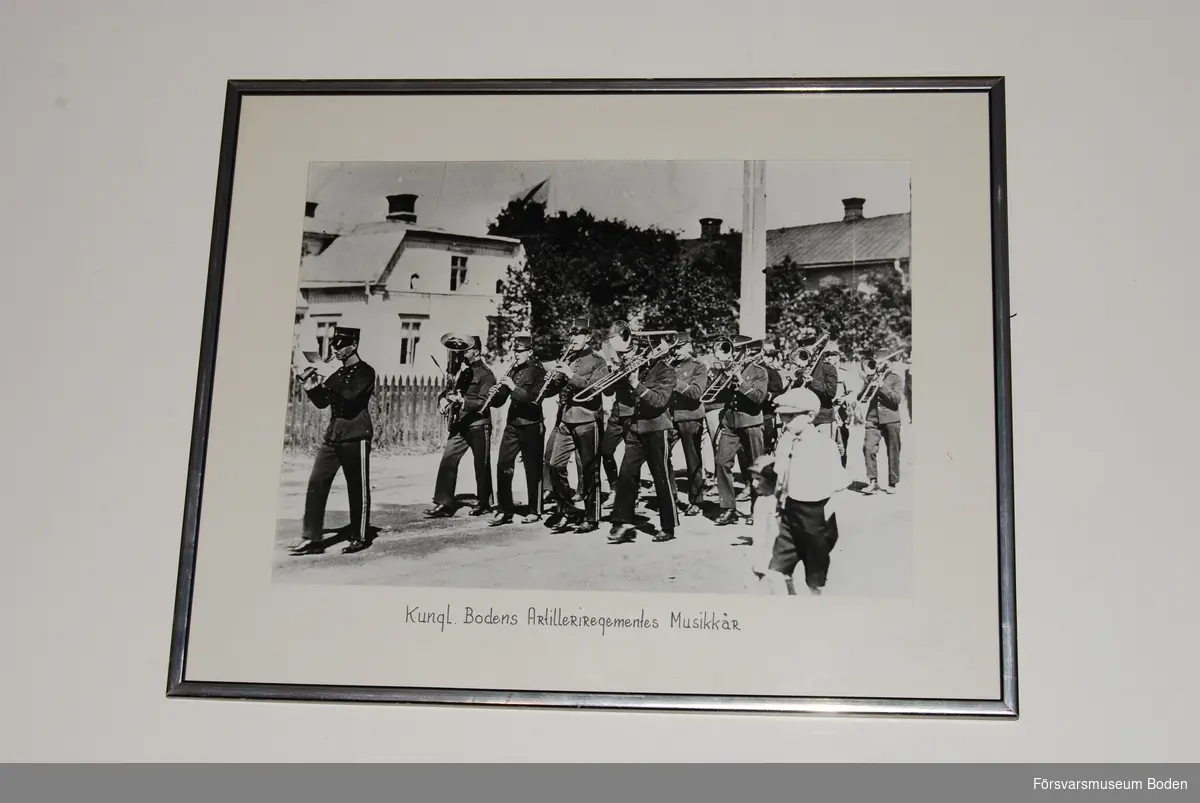 Inramat och glasat fotografi föreställande Bodens artilleriregemente A 8:s musikkår på marsch. I täten går musikstyckjunkare Ernst Melin, som fick denna befattning 1925.