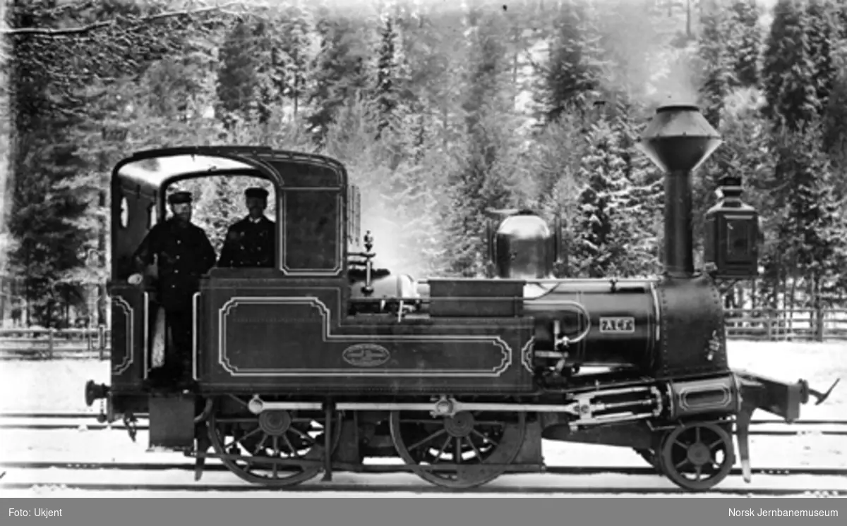 Vinterbilde av damplokomotiv type III nr. 21 "Alf" med lokpersonalet i førerhytta