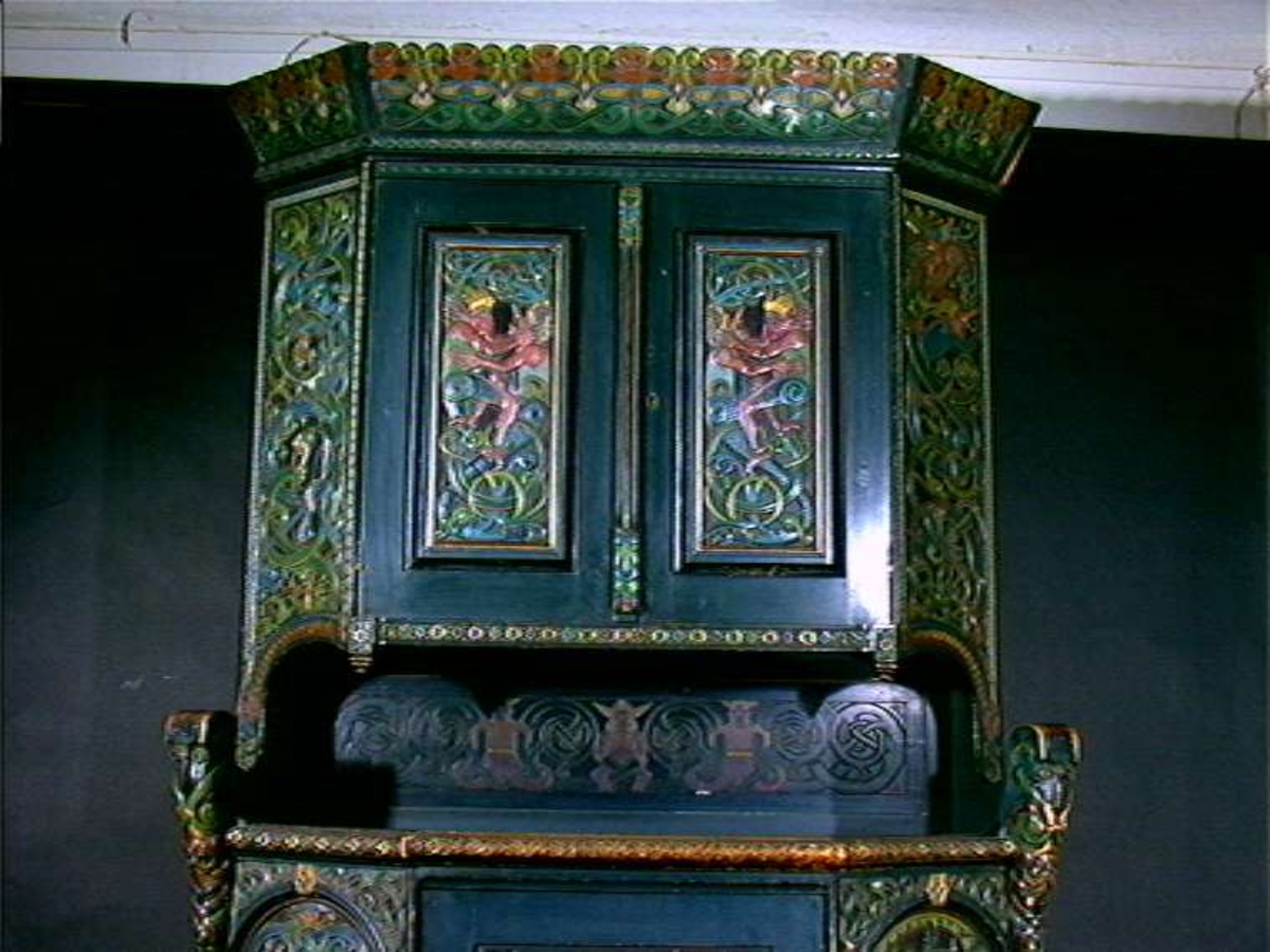 Skåret av treskjæreren Lars Kinsarvik (1846-1925), som utviklet sin særegne variant av drakestilen. Kinsarvik drev egen treskjærerskole, og var fra slutten av 1880-årene lærer ved Kristiania Kunstindustrimuseum.