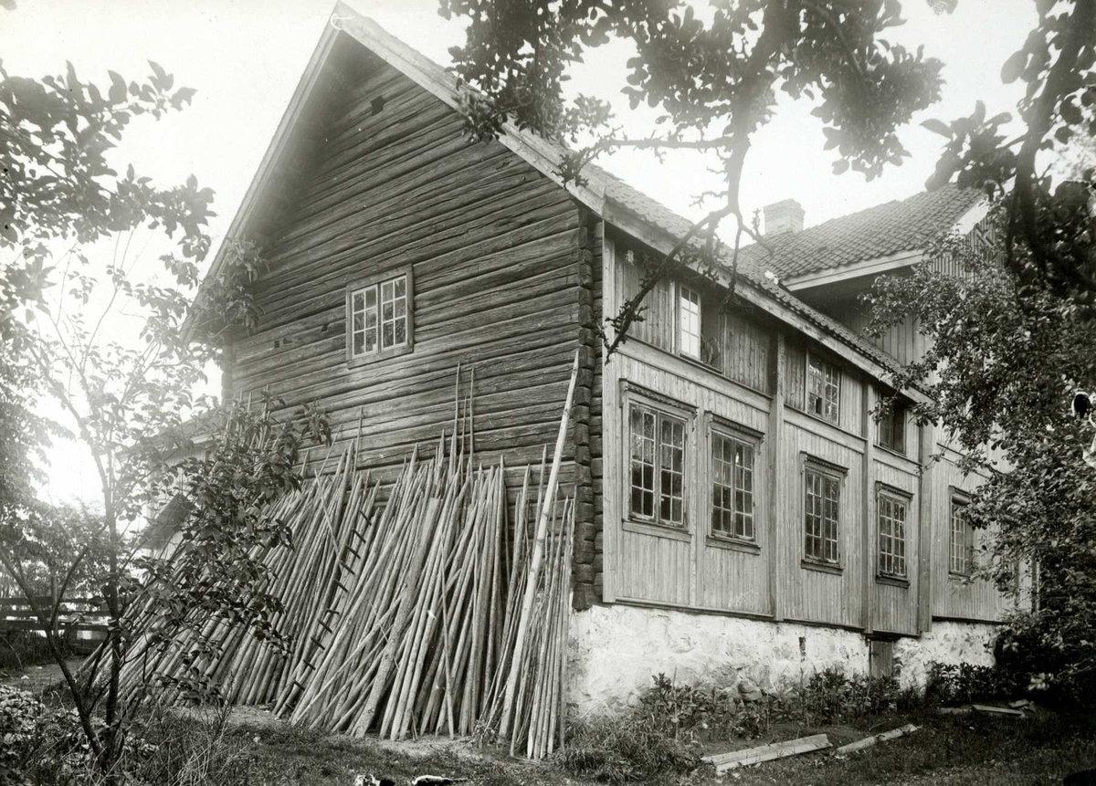 Brotner, Ullensaker, Øvre Romerike, Akershus. Delvis panelet tømmerhus med staur lent mot kortveggen.