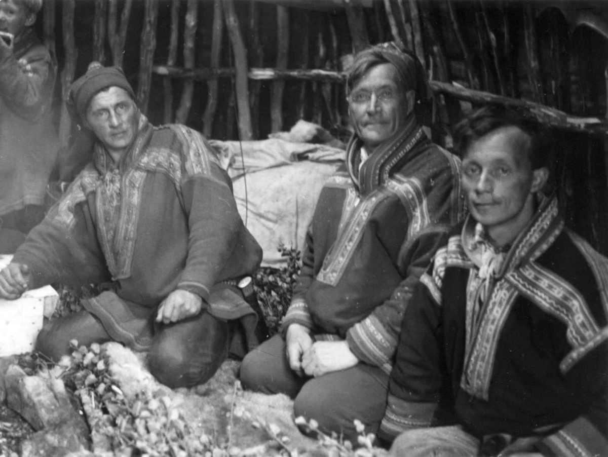 Medlemmer av familien Eira sitter på gulvet i gammen. Kvænangsfjell 1956.