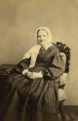 Portrett. Eldre kvinne sittende i fotoatelier, helfigur, Osl