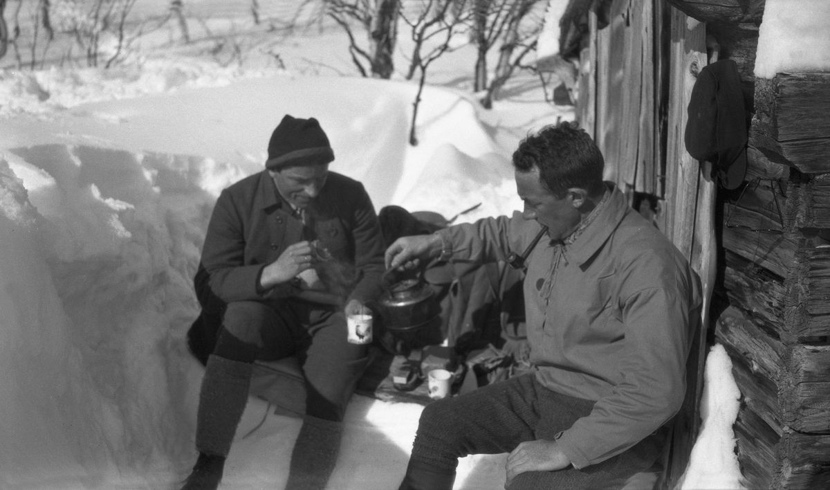 Fritjof Arentz og Sigurd Mørch sitter nedgravd i snøen ved et uthus ved Kongens Grube, Rødsjøenvatnet. Fotografert 1929.