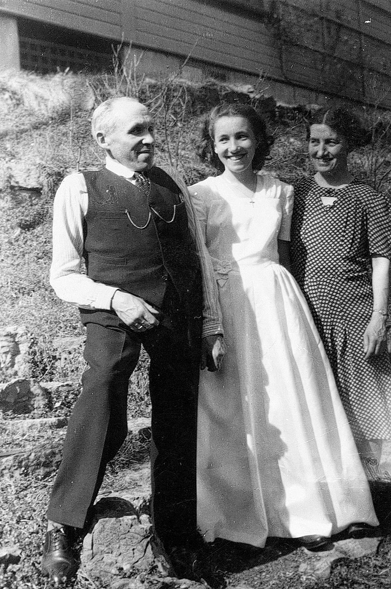 Anne-Marie Fouglis konfirmasjon. Her i hagen mellom mor og far, Jar, Bærum, Akershus. Fra venstre: Karl Fougli, Anne-Marie Fougli og Hjørdis Fougli.