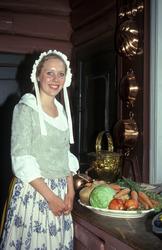 Vert i bydrakt på kjøkkenet med mat på bordet i Chrystiegård