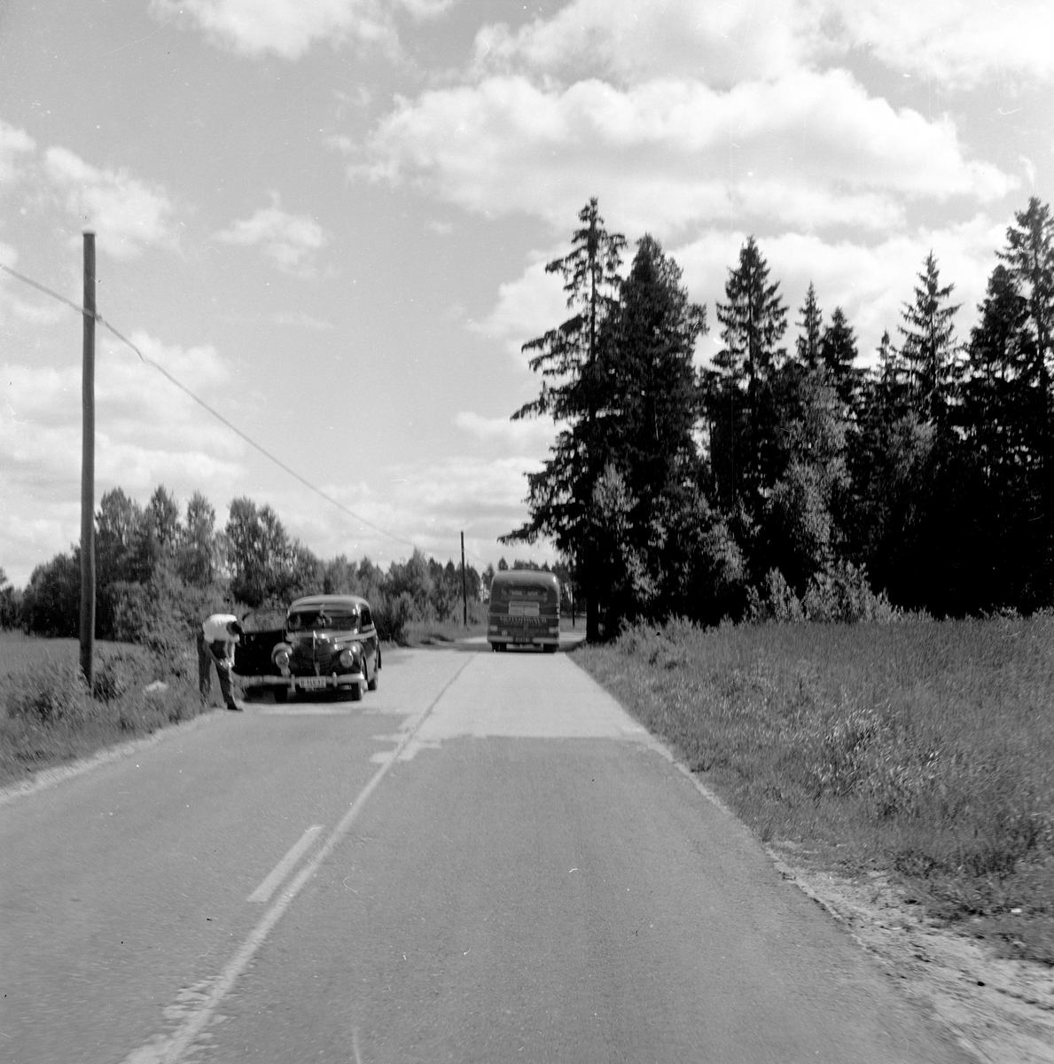 Langs Riksvei 1 står en bil parkert i den det ene feltet. Fotografert 7. juli 1958.