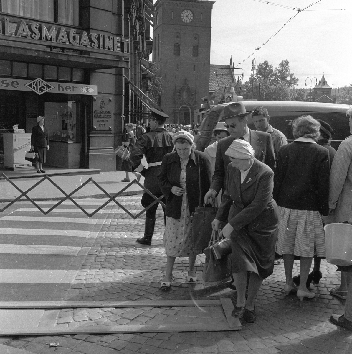 Fotgjengere går utenom nymalt fotgjengerfelt i krysset Møllergata og Stortorvet ved Glasmagasinet, Oslo. Fotografert mai 1959.