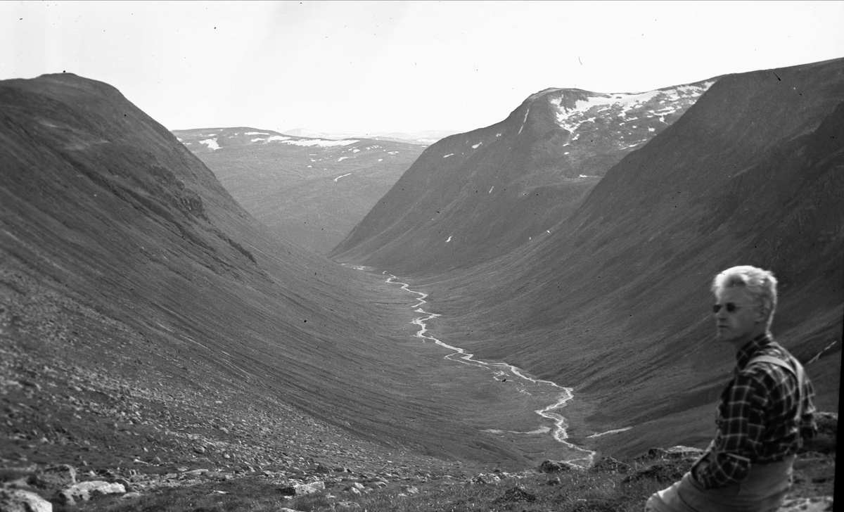 Panoramautsikt over Ottdalen med elven Otta, Sunndal, Møre og Romsdal. Mann sitter  i forgrunnen. Fotografert 1940.