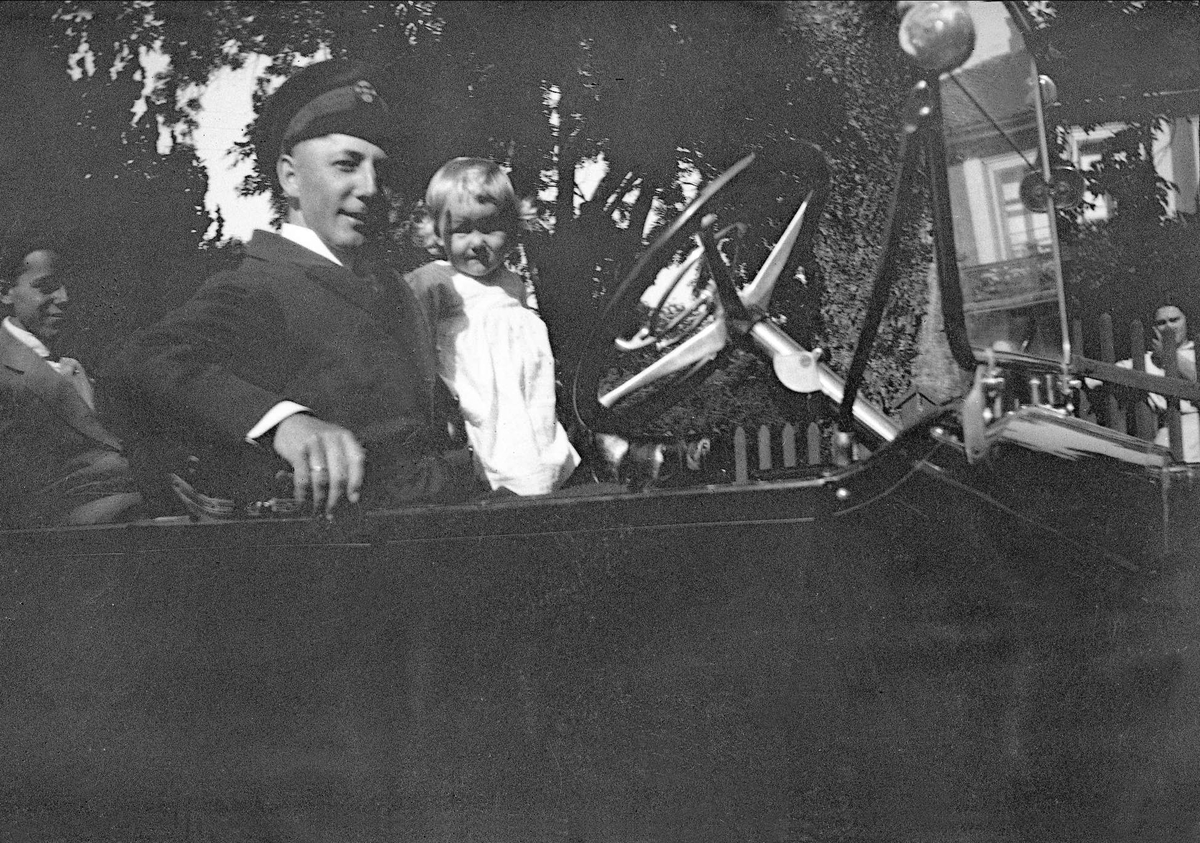 En mann og to barn i en åpen bil. Robsahm og Lund.