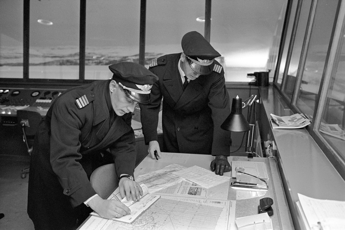 Serie. Ombord på SAS flyet til Tromsø. Flyfoto over snødekkete fjell. To flyvere i flytårnet. To menn og en kvinne, ant. Eva Lie, sitter rundt et bord. Fotografert desember 1965. 