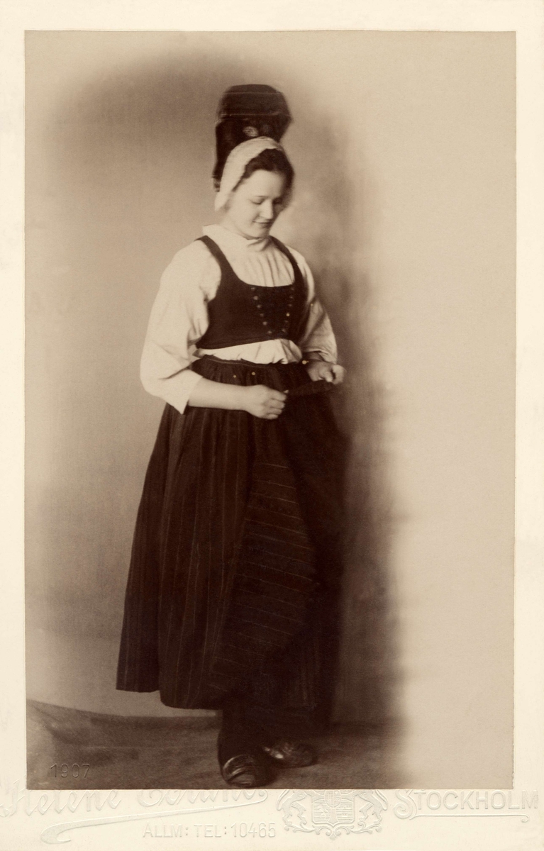 En kvinna klädd i dräkt från Häverö, Uppland med den typiska högmössan.