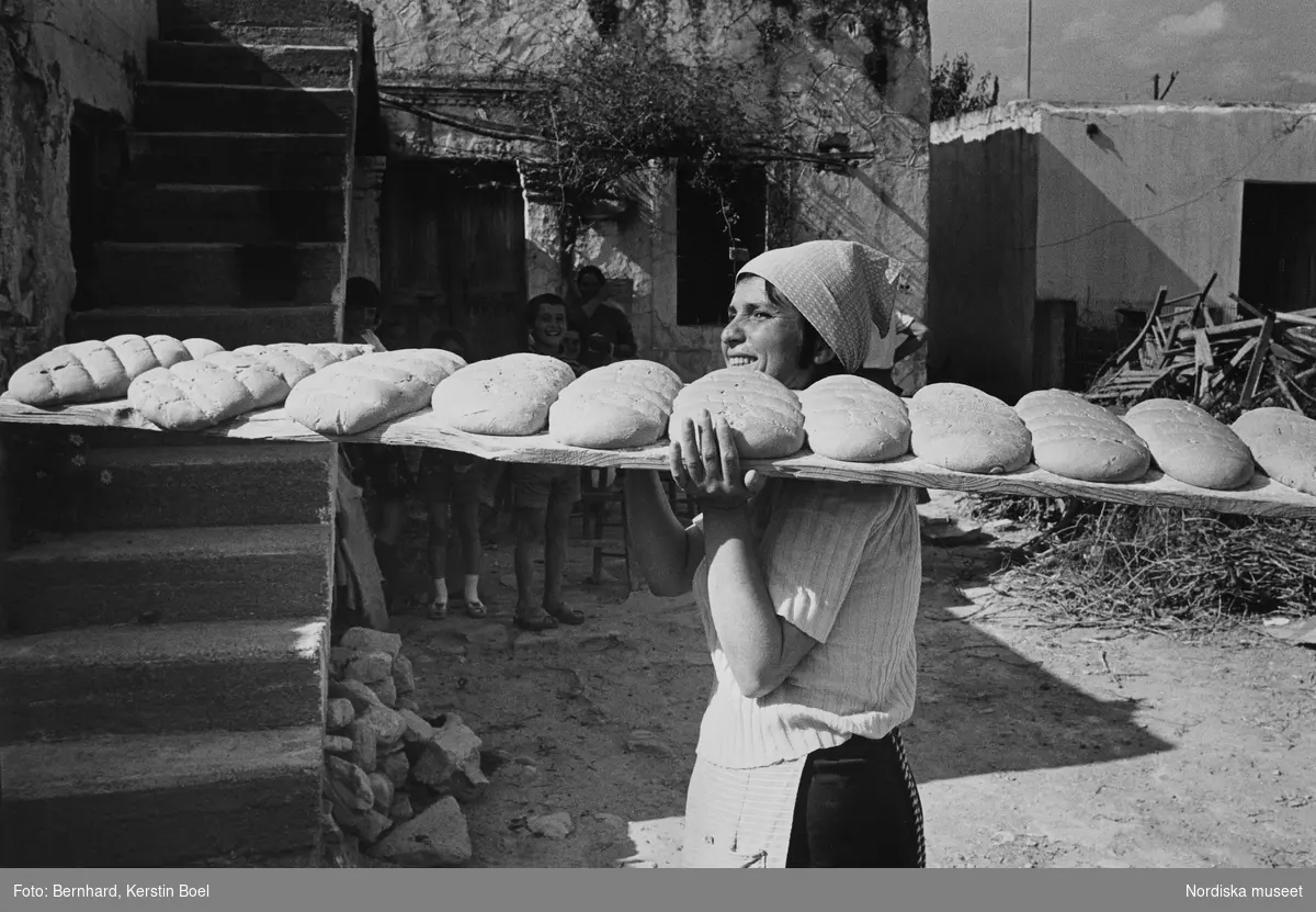 Kvinna bär planka med bröd för gräddning. Kreta.