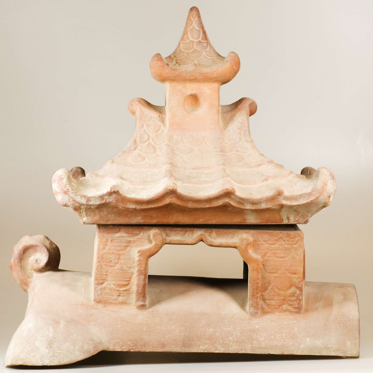 Del av större skulptur eller byggnadsdekoration föreställande kinesisk byggnad på ryggen av ett djur. Består av två delar, dels den nedre delen av byggnaden stående på en djurrygg, dels taket på byggnaden.