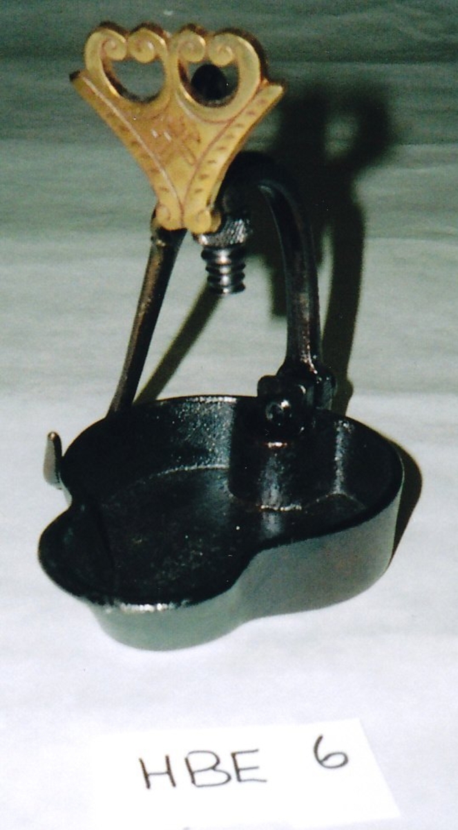 Form: Rund skål med "tunge" og kant til tran, bøyle festet i bakkant av skåla som når midt ut på skåla, krok på toppen til å henge lampa i.
