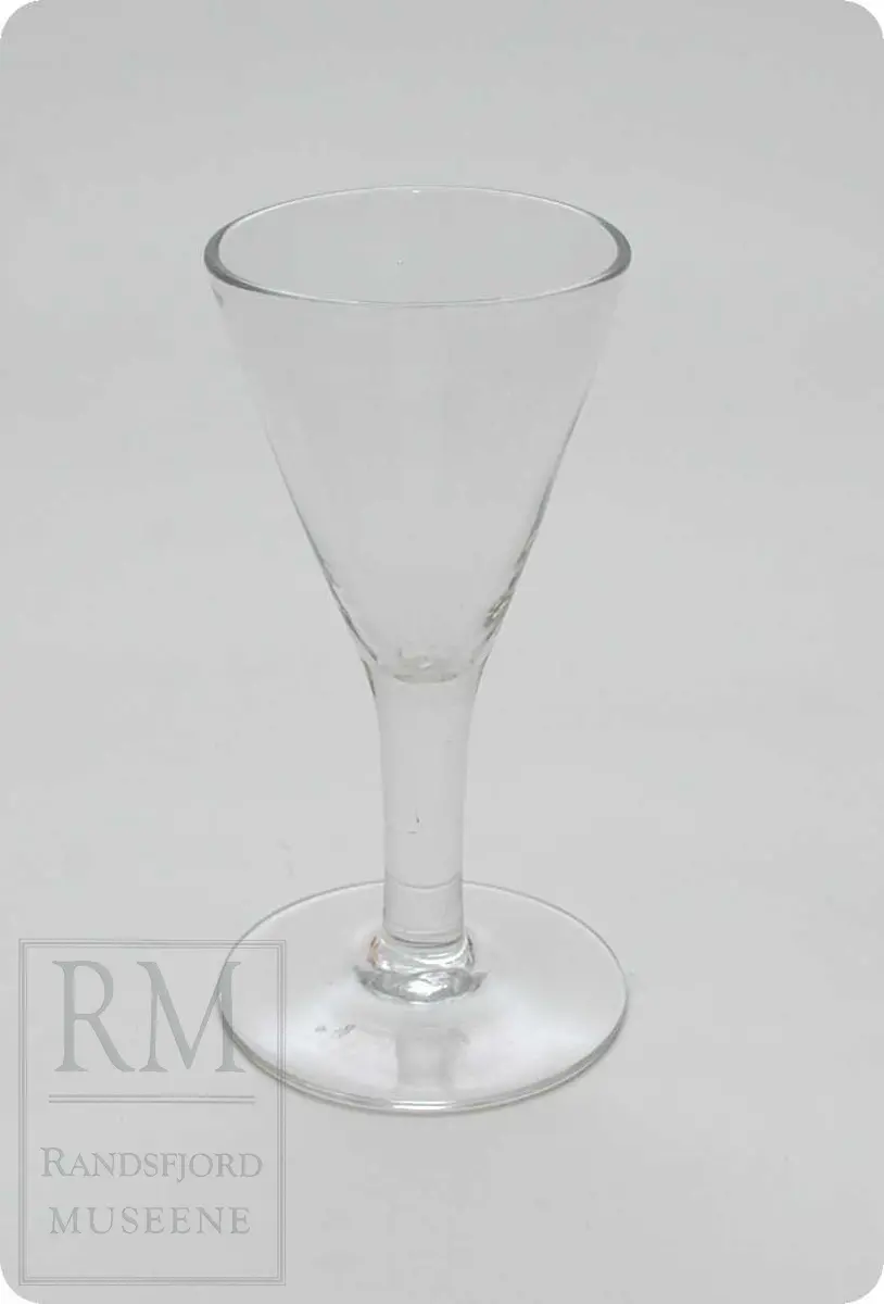 Spissglass. Flat fot på høy stett. Traktformet cupe med rette kanter.