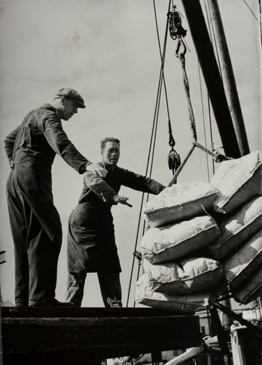 To menn, Olaf Ree og Dagfinn Stangeland, lossar sekkar på Øglændskaien