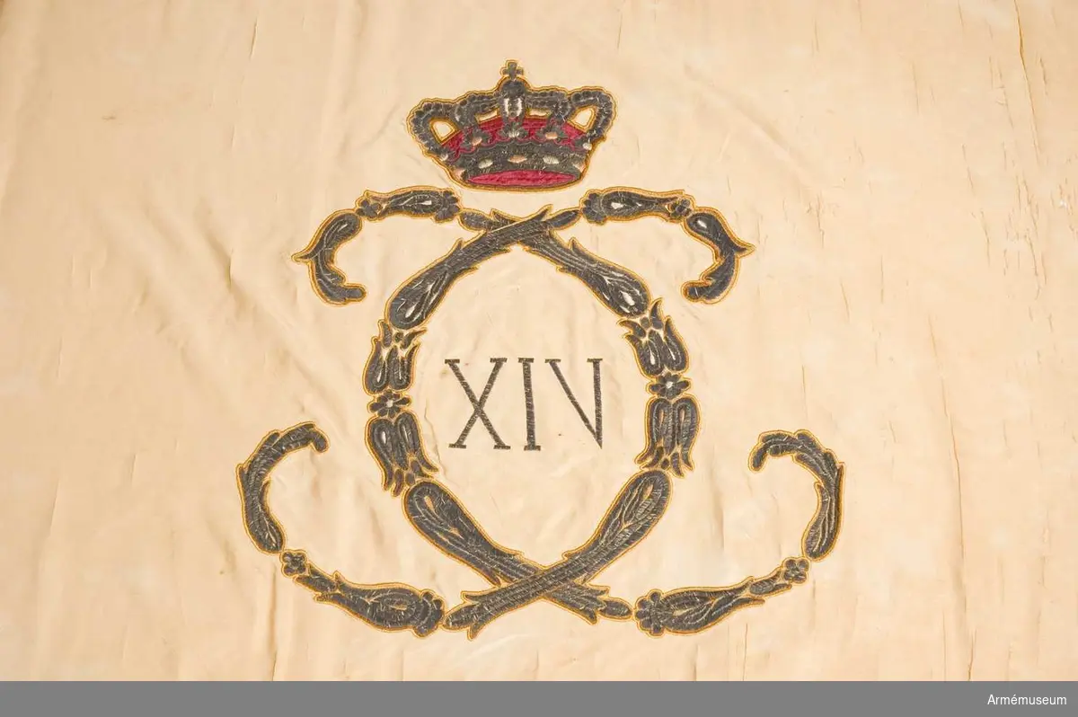 På det gulvita kyprade fansidenet sitter i mitten ett broderat monogram föreställande två motställda "C" inneslutande "XIV". Broderiet utfört i plattsöm med silke och silvertråd. Ovanför monogrammet sitter en kunglig krona utförd i plattsöm med foder i rött silke. I fanans hörn sitter snedställda kronor i brunt silke. Ett fragment av fanan på vilken en av de fyra kronorna sitter ligger löst och hoprullat tillsammans med fanan. Fanspetsen har Karl XIV Johans monogram, dock mycket ärgat. Fanstången är gulvitmålad. Kravatten, den lilla del som återstår, är uppsydd på ett bomullsband.