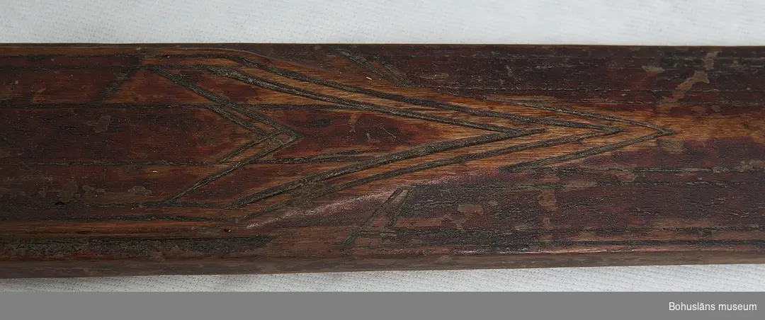 Skidorna har skuret mönster, målade i brunröd färg. Fotgreppet med näver och tvinnade vidjor; bindslen i läder med sölja i metall, skador, delar saknas.
Staven av trä, omålad; trygan/trugan av metall (järn), päls och horn.

Ur handskrivna katalogen 1957-1958:
Skidor, 2st. , + 1 stav
L. 322,5 resp. 225. Träskidor, som tillhört jägaren och förf. L. Lloyd. 1850 - talet.
Stavens L:118 Värmland. Hela staven rostad vid kringlan.

Lappkatalog: 40

Bilagepärmen:
Artikel "Björnjägaren L. Lloyd av William Andrew Macfie, 1913.
Artikel i På skidor, Skidfrämjandets Årsskrift 1942. Jirlow, Ragnar. Ur skidlöpningens hävder i Särna.