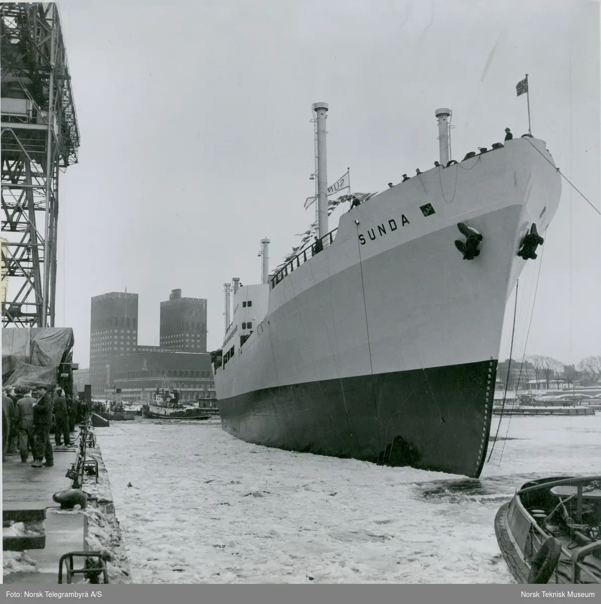 Cargolineren M/S Sunda, B/N 504 blir buksert til kai etter stabelavløpningen på Akers Mek. Verksted 25. mars 1954. Skipet ble levert i 1954 til J.L. Mowinckels rederi. Oslo Rådhus i bakgrunnen.