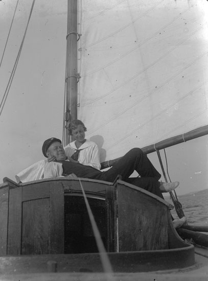 Enl. text i blå bok: "Man och dam på rufftaket, segelbåt."
