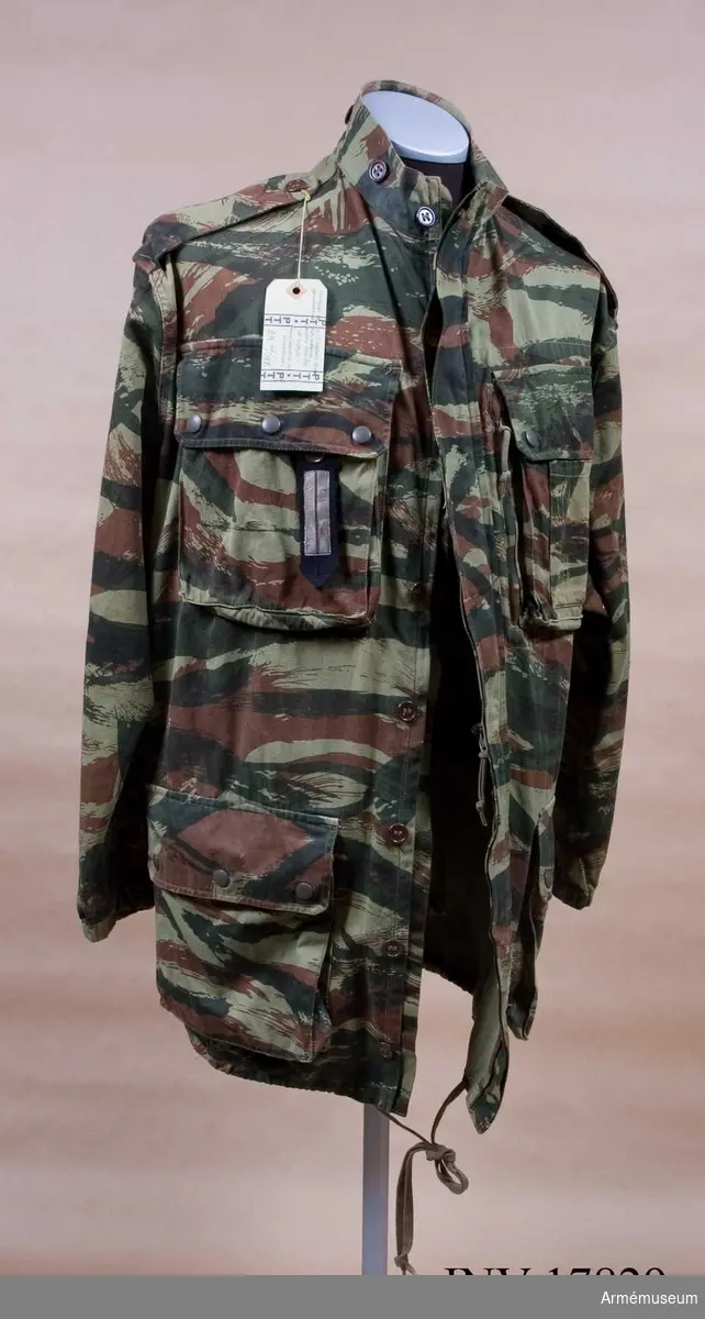 Grupp C I.
Jacka "Veste camouflage".
Ur uniform för löjtnant vid 1 ére regiment de Hussards parachutiste Algériet, 1959-1960, Frankrike.
Uniformen består av jacka, byxor, basker, livrem, kängor, pistolhölster och fältflaska med överdrag.