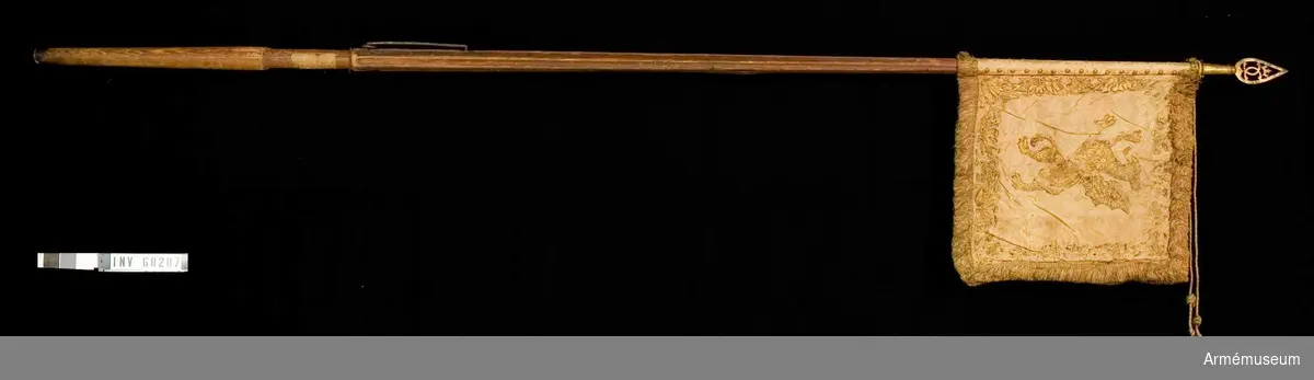 Duk: Tillverkad av dubbel, rosa sidendamast (mycket blekt). Duken fäst med tre rader tennlikor utan band.

Dekor: Målad på inre sidan en gyllene, rödskuggad grip (Östergötlands vapen); längs kanten bård av stiliserade bladverk, kronor och korsade palmkvistar i rödskuggat guld; på yttre sidan Karl XI:s namnchiffer, dubbelt C under sluten krona, prydda med pärlor i silver och stenar i rött och grönt; bården liknar innersidans, allt i rödskuggat guld. Kantbård av silke och guldtråd i laxrosa.

Stång: Tillverkad av trä, kannelerad, rödmålad; löpande bärring; grepp; holk och spets av förgyllt järn(?), spetsbladet med dubbelt C under öppen krona.
