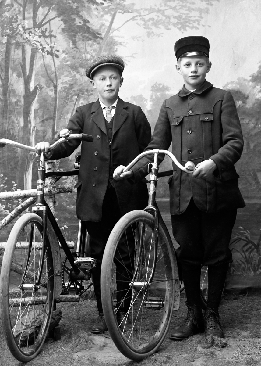 Ateljéporträtt av två pojkar med cyklar.