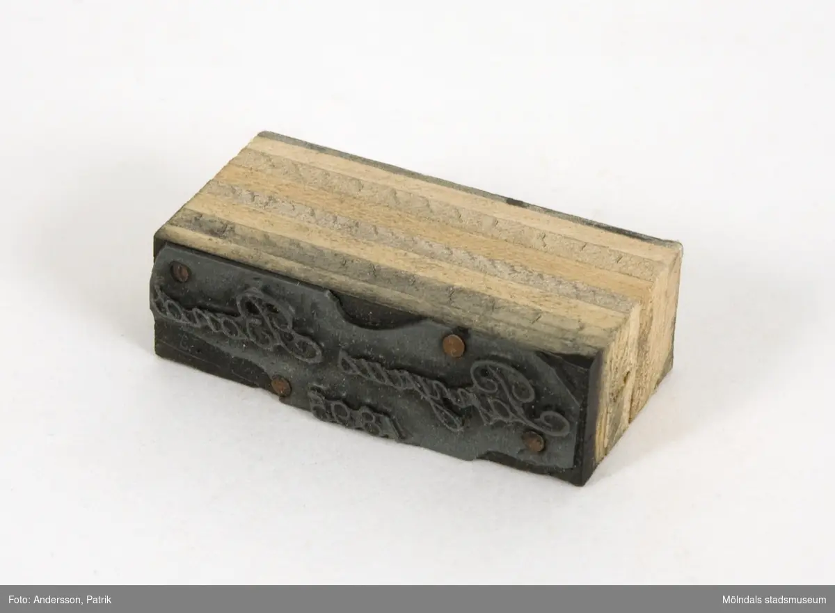 Trycktyp av metall, monterad på träkloss, från Papyrus. Texten på typen: "Papyrus Bond 1895". Motivet är spegelvänt för att det skall överföras rättvänt vid tryck på papper. 