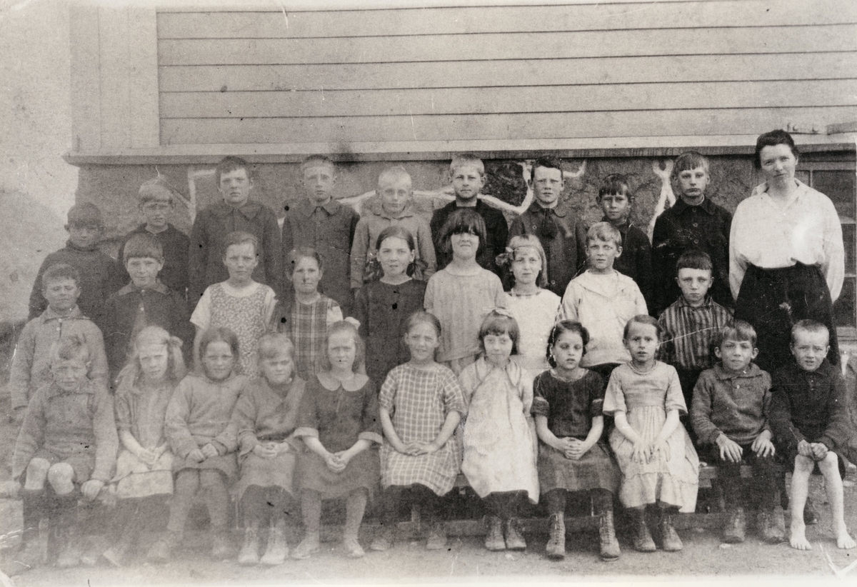 Flickor och pojkar på Toltorpskolan, sittande och stående i grupp. En av pojkarna är barfota.