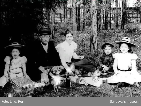 Alby 1898. Föräldrar samt tre barn,  dricker saft och äter bullar i skogsbrynet.