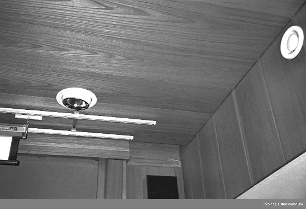 Mölndals stadshus, juni 1994. Del av vägg och tak klädda i ek-panel i ett sammanträdesrum. I taket sitter skenor samt en lampa. På väggen finns en ventil.