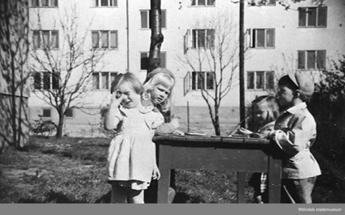 Fyra barn utomhus vid Krokslätts daghem, Dalhemsgatan 7 i Krokslätt 1949. Bostadshuset i bakgrunden är Dalhemsgatan 10 - 12.