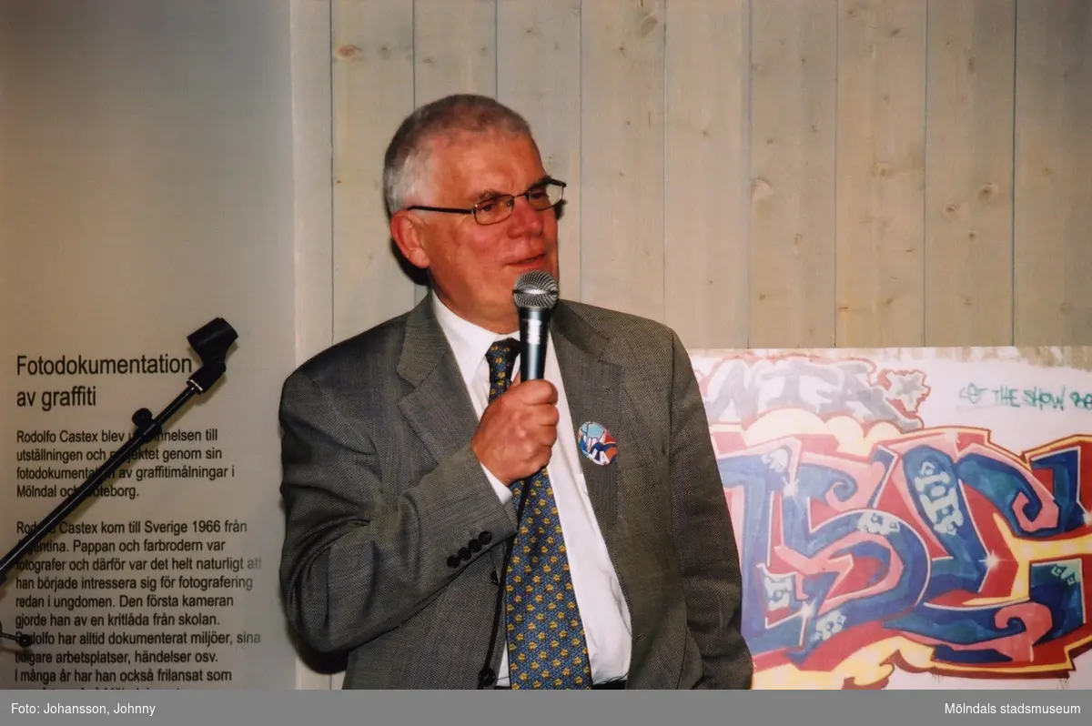 Professor Lars Nordström, ordförande i Västra Götalands Kulturnämnd, håller tal vid invigningen av utställningen "Alltså finns jag" på Mölndals museum, år 2003.