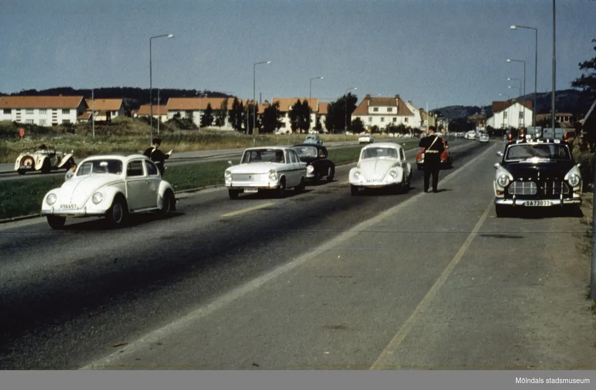 Poliskontroll på Kungsbackavägen i Mölndal, då vi fortfarande hade vänstertrafik, cirka 1965 - 1966. Högertrafik infördes september 1967. I bakgrunden ses bebyggelse på Broslätt.
