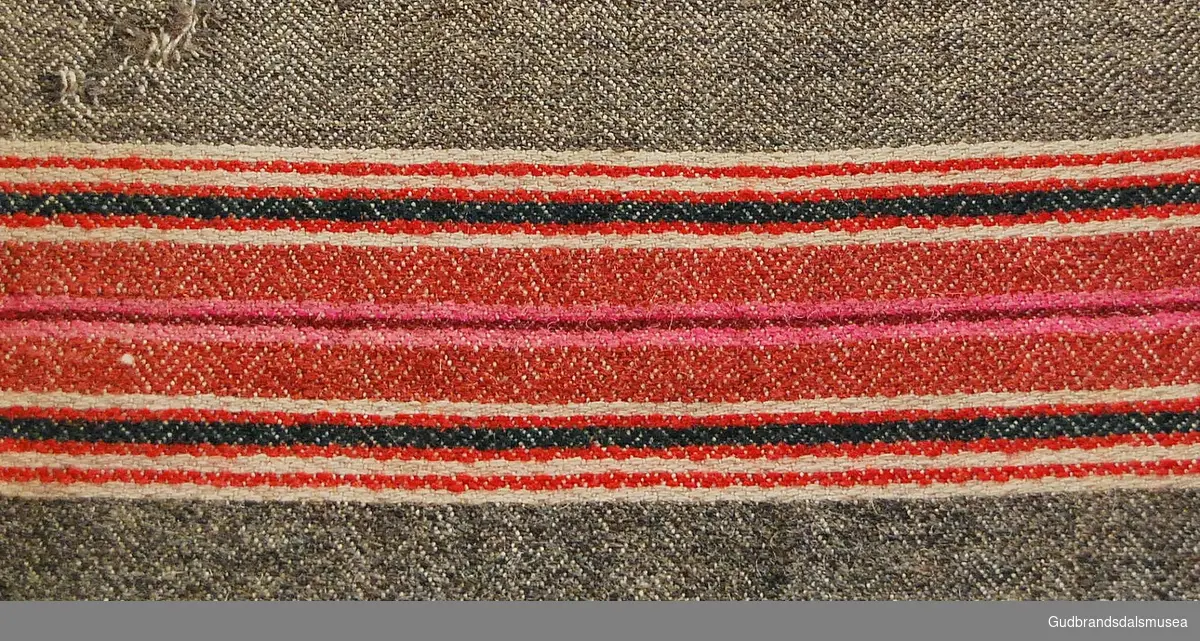Stort rektangulært putevar i vevd ull. Vertikale striper i ulike farger. Åpning på ene kortsiden som fortsetter et stykke langs ene langsiden. 