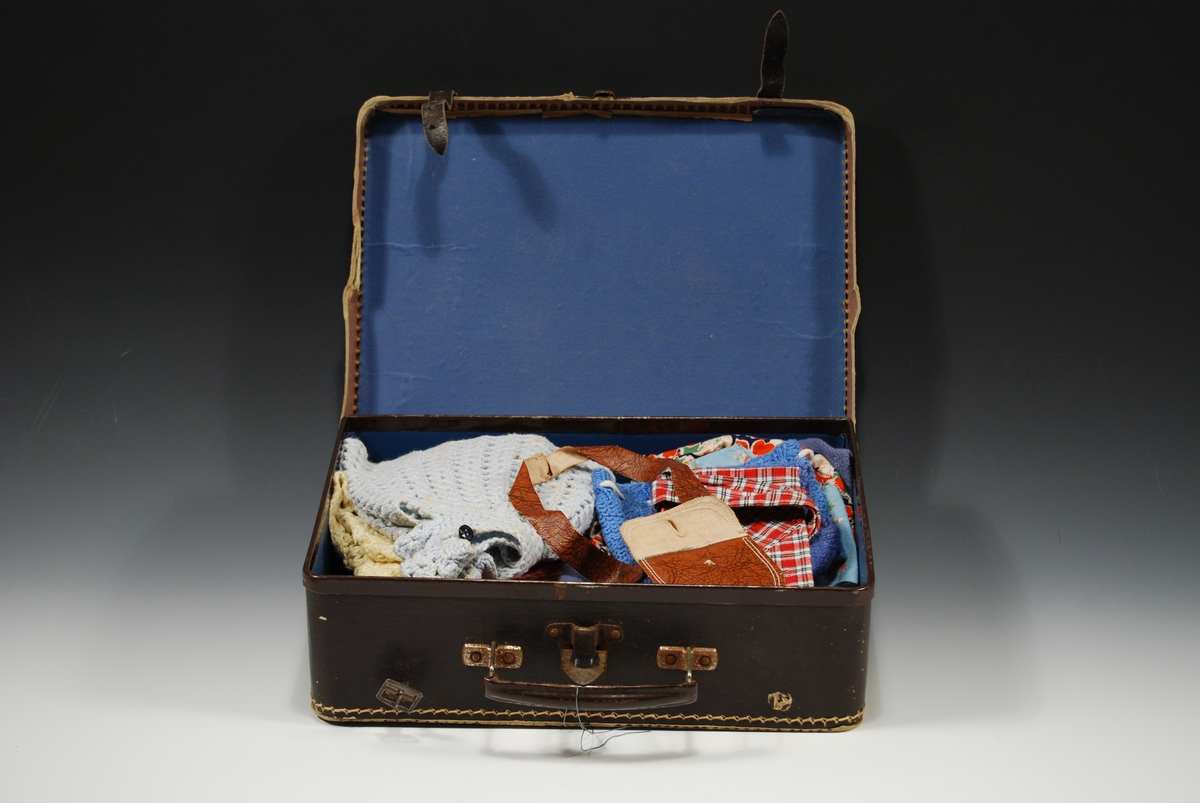 Koffert fylt med hjemmelagde dukkeklær, strikket og sydd.