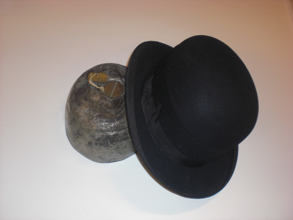 Hatt med tillhörande plunta. Användes för spritsmuggling under motbokstiden 1922-55. Totalt lyckades man i denna hatt smuggla 200 liter sprit och blev aldrig upptäckt av tullen.
