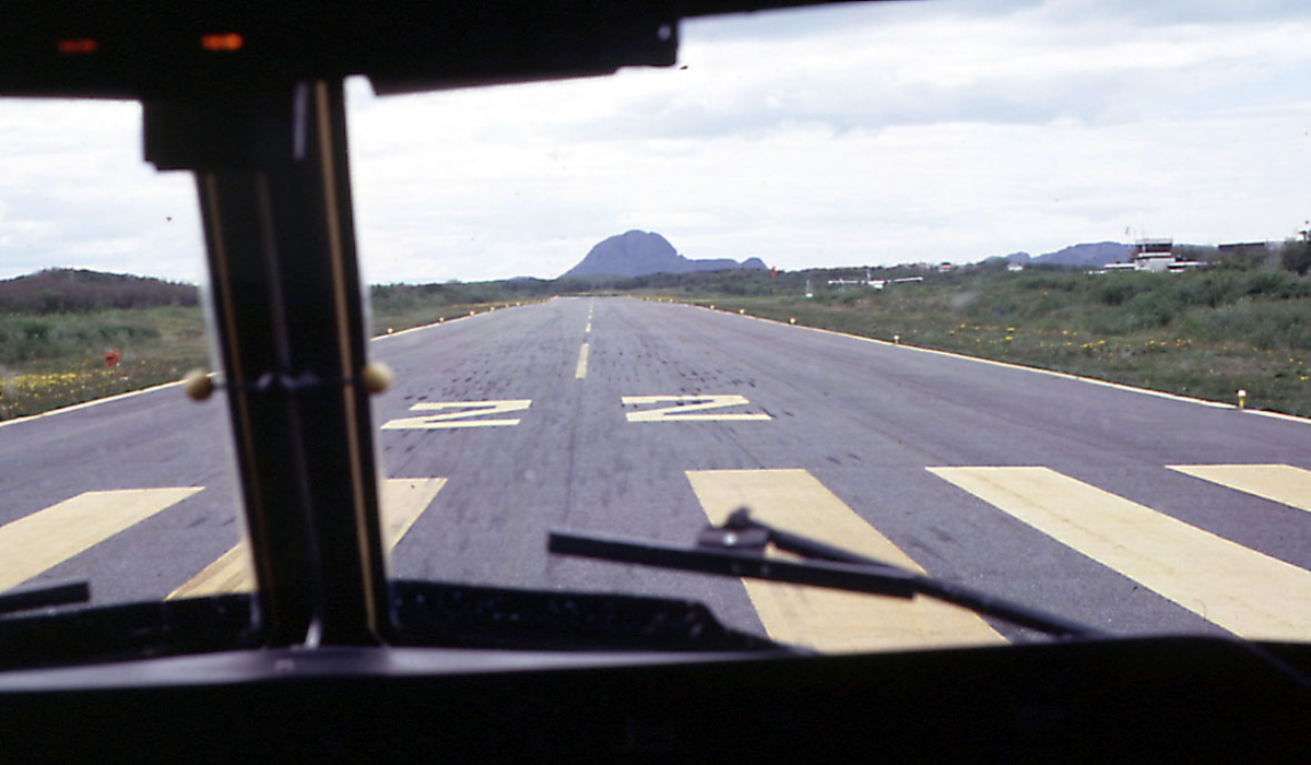 Lufthavn, rullebanen sett fra cokpiten ombord i WF 705.  ett fly og kontrolltårnet i bakgrunnen
