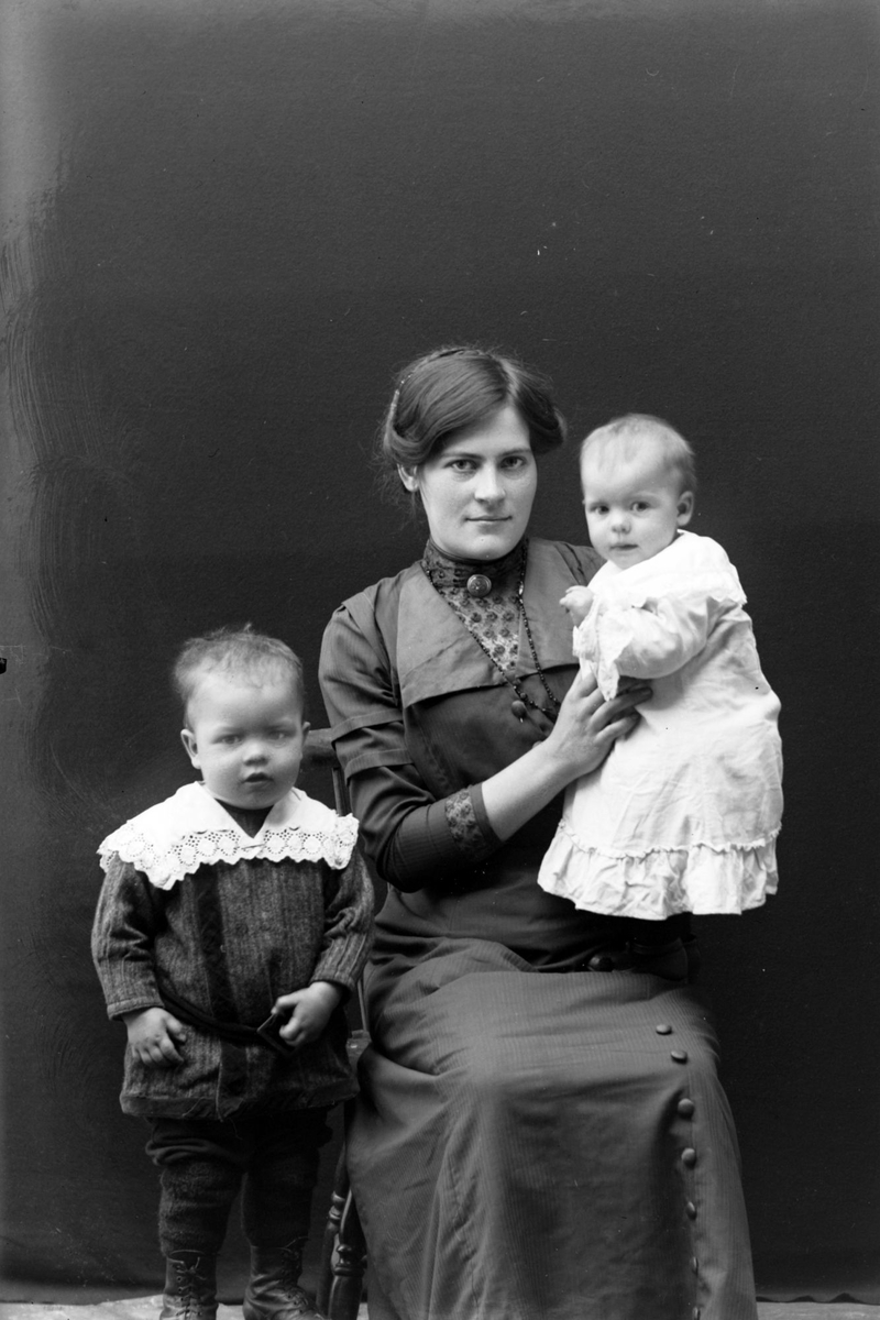 Studioportrett av ung kvinne med to småbarn.