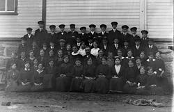 Gruppebilde av konfirmanter utenfor Tysfjord kirke. Prest i 