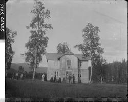 Oversiktsbilde av et våningshus med noen mennesker i forgrun