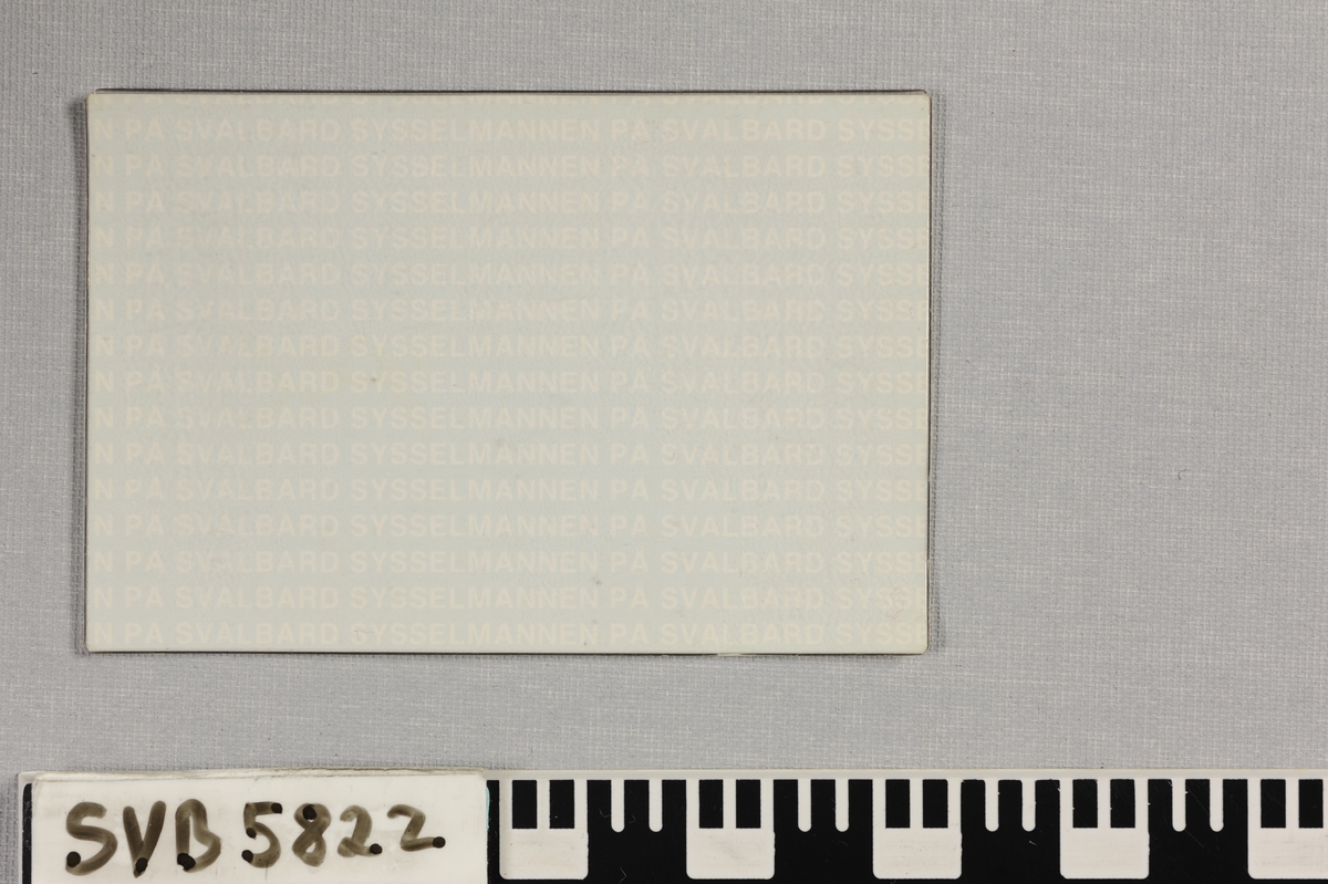 Firkantet stykke papp med trykt tekst i en transparent plastlomme.