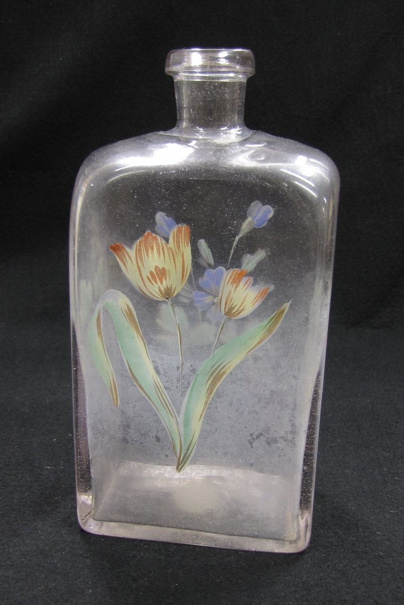 Brännvinsflaska av glas. Flaskan har målad dekor i form av blommor.